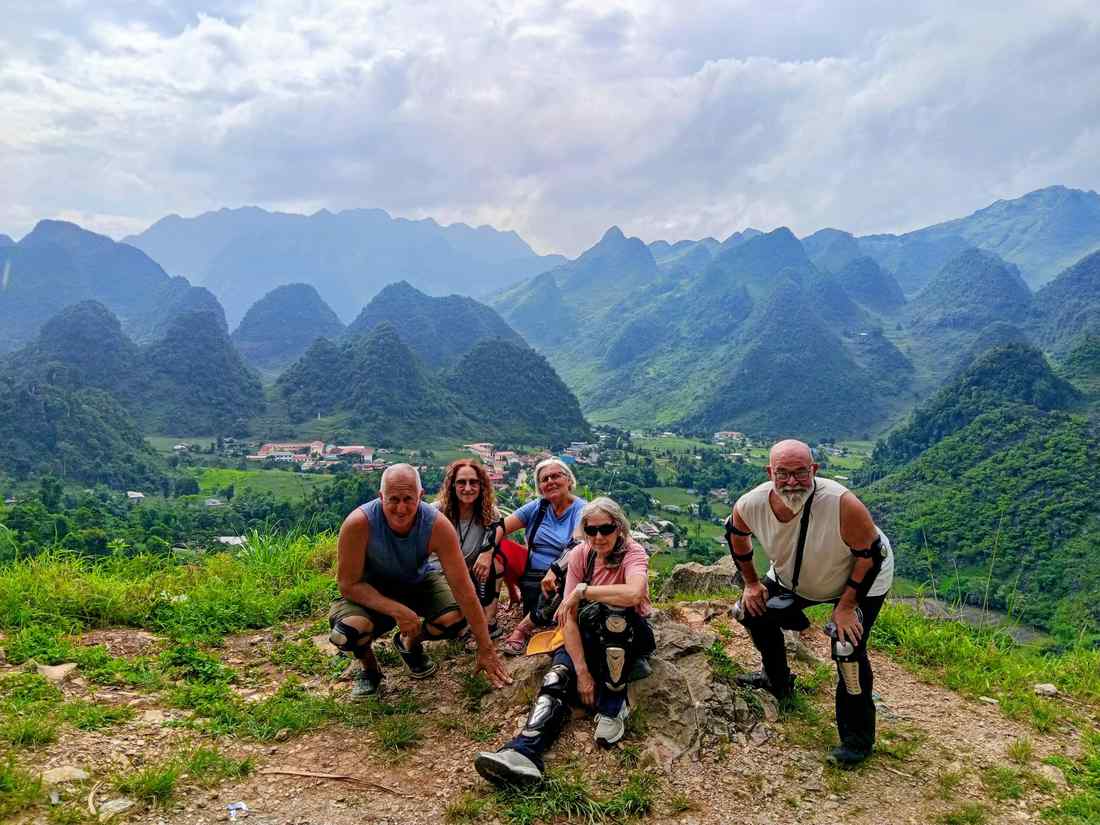 Cinco viajeros posando en un mirador con montañas verdes de Vietnam