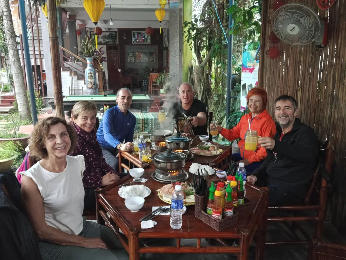 Viajeros de un grupo afín brindando juntos en una comida durante un viaje por Vietnam