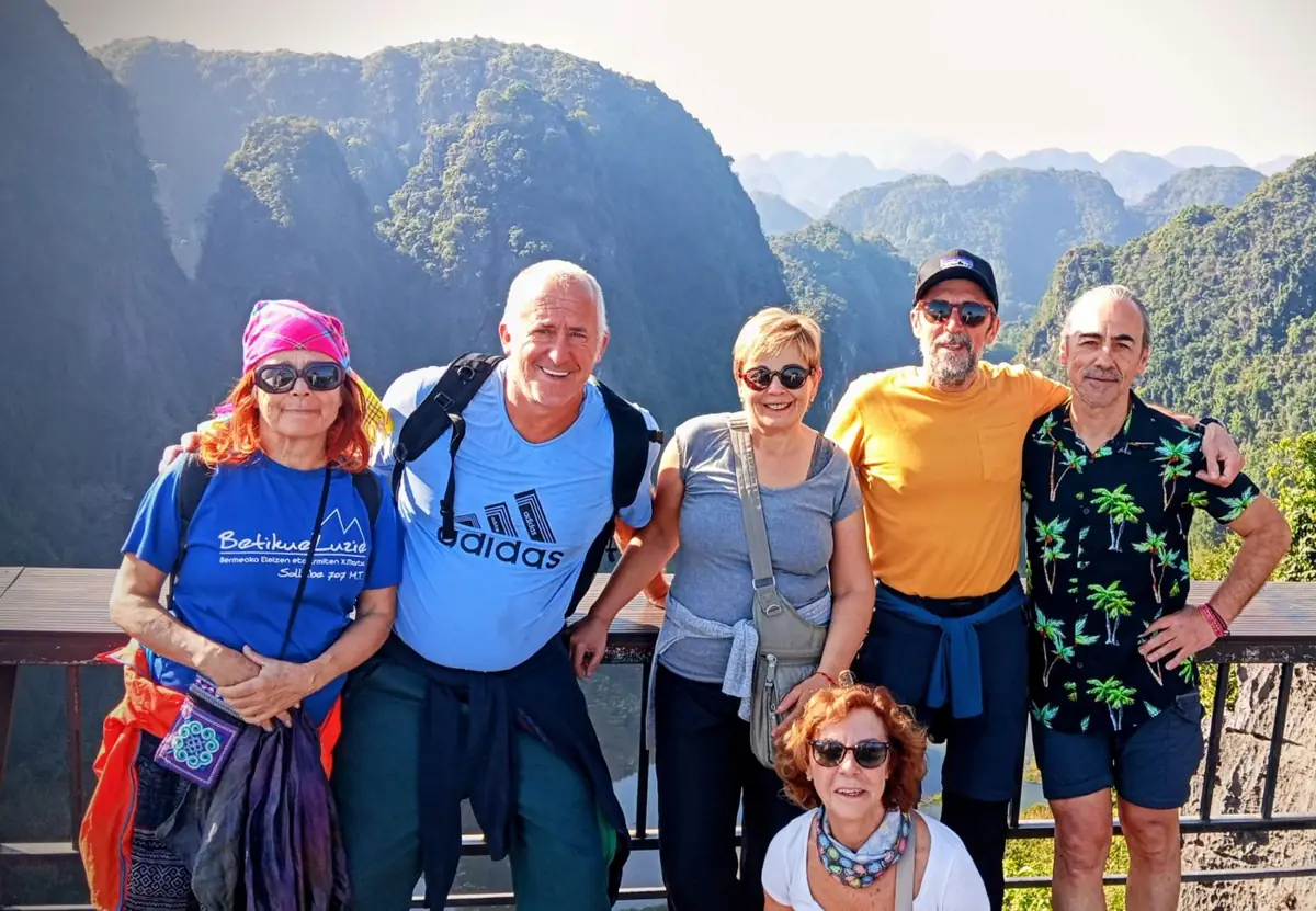 Grupo de viajeros sonriendo juntos en un mirador con montañas al fondo en Vietnam