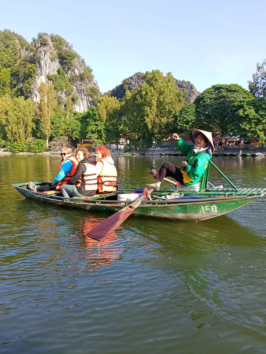 Viajeros en una barca tradicional sobre un río rodeado de montañas en el norte de Vietnam